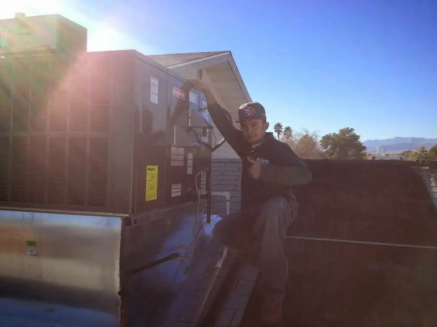HVAC technician performing Air Duct Repair on a rooftop unit in Topeka